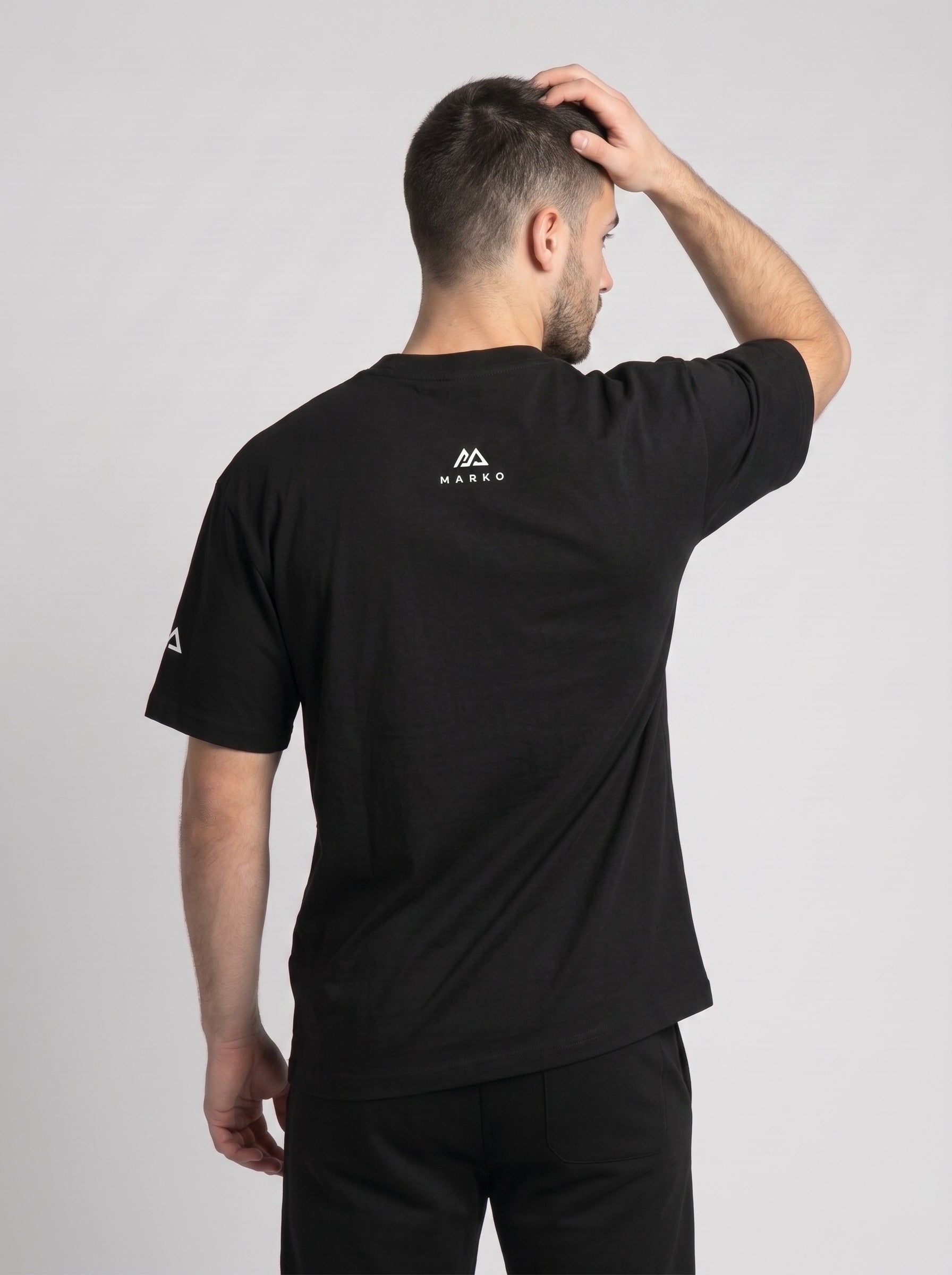 Model wearing the black 300 Heavyweight Tee, back view, Marko two-peak mark at the back yoke