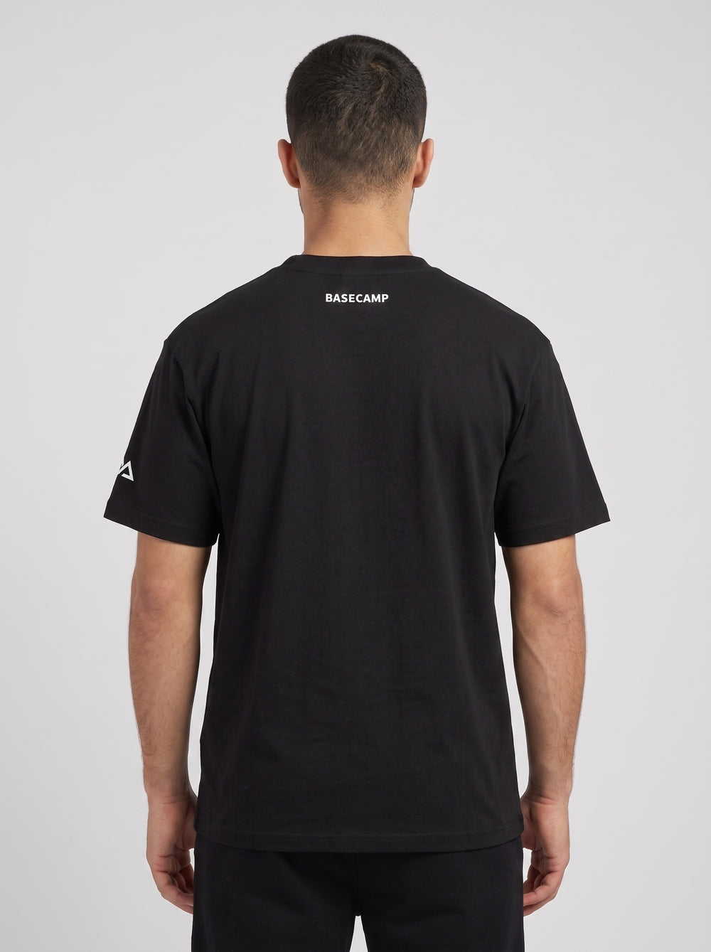 Model wearing the black BASECAMP Heavyweight Tee, back view, BASECAMP printed at the back yoke and the two-peak mark on the sleeve