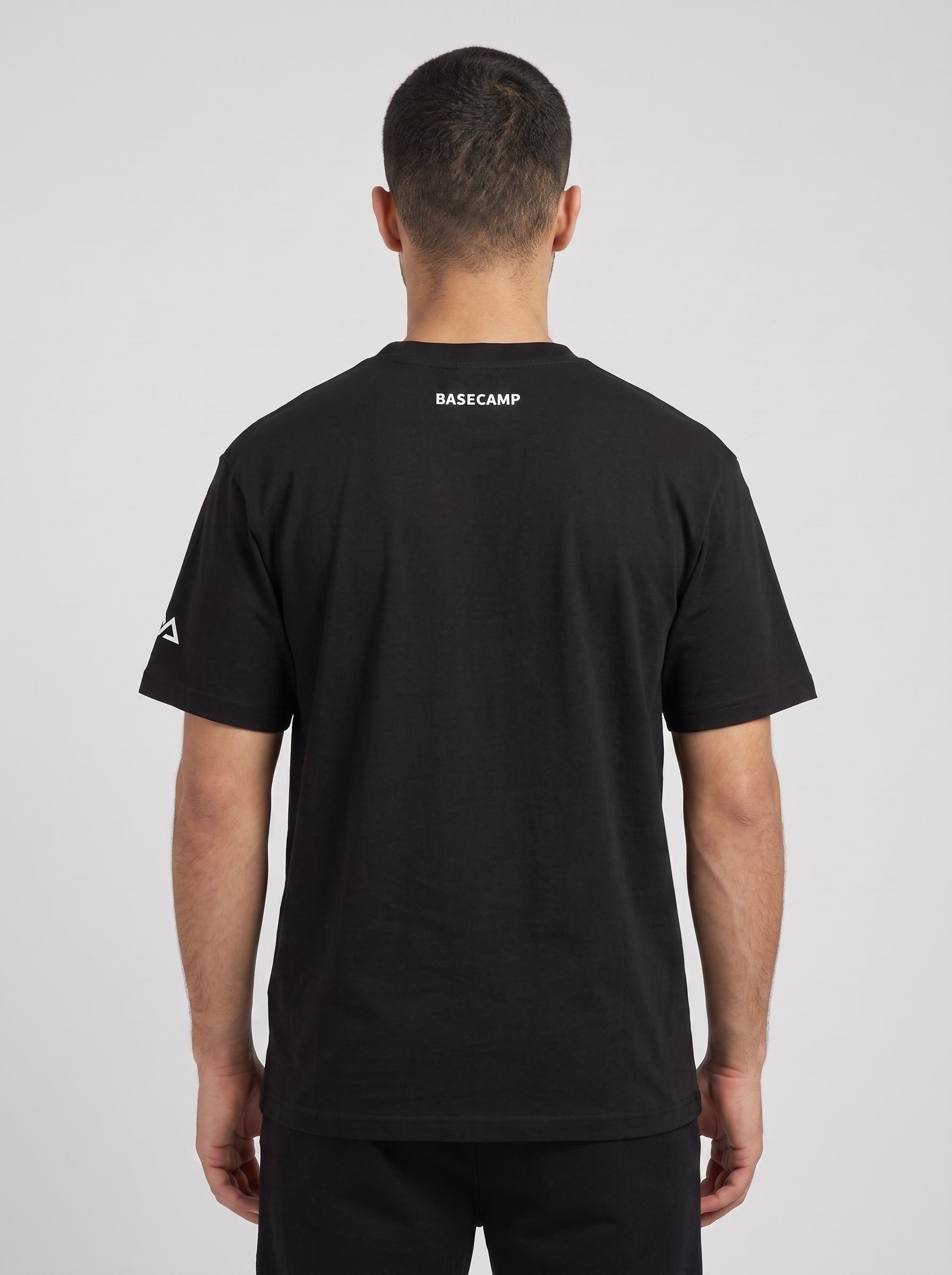 Model wearing the black BASECAMP Heavyweight Tee, back view, BASECAMP printed at the back yoke and the two-peak mark on the sleeve