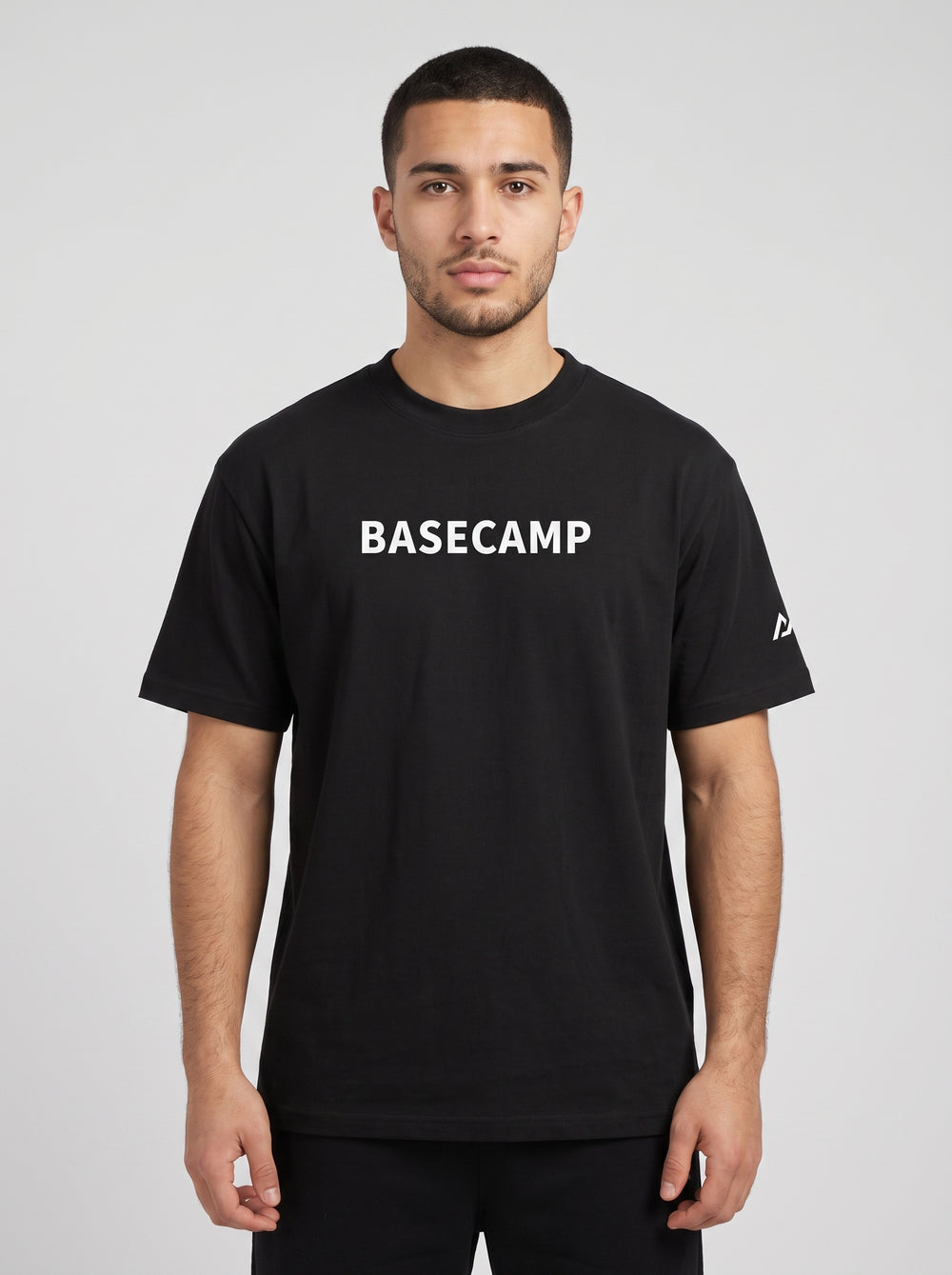 Model wearing the black BASECAMP Heavyweight Tee, front view, BASECAMP wordmark across the chest and the two-peak mark on the sleeve
