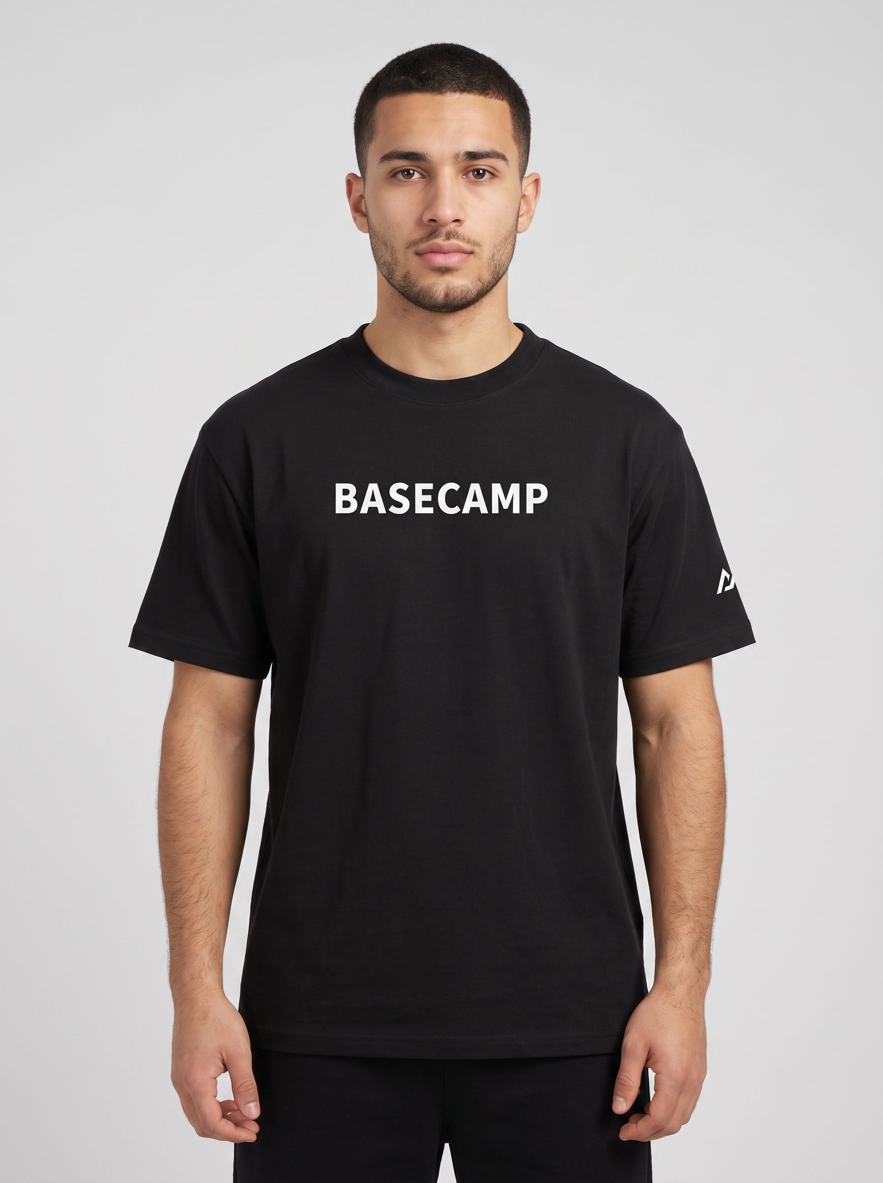 Model wearing the black BASECAMP Heavyweight Tee, front view, BASECAMP wordmark across the chest and the two-peak mark on the sleeve